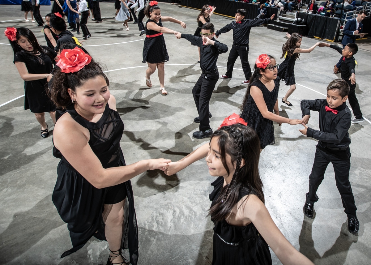 Group of young people all dressed in black with pink accents, swing dance in pairs