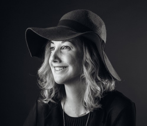 Black & white photo of smiling person wearing floppy hat.